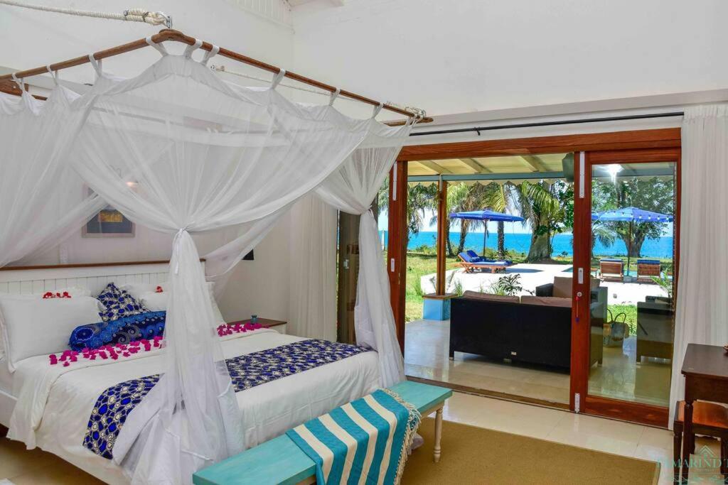 MaziziniTamarind Tree Zanzibar的一间卧室设有一张天蓬床,享有游泳池的景色