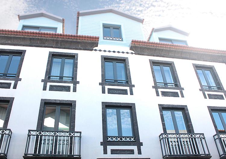 奥尔塔Faial Marina Apartments 1的白色的建筑,设有黑窗和阳台