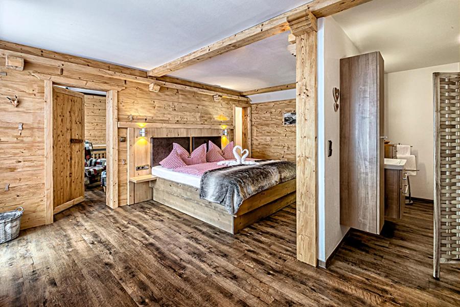 国王湖Almhotel Grünsteinblick的卧室设有木墙和一张带粉红色枕头的床