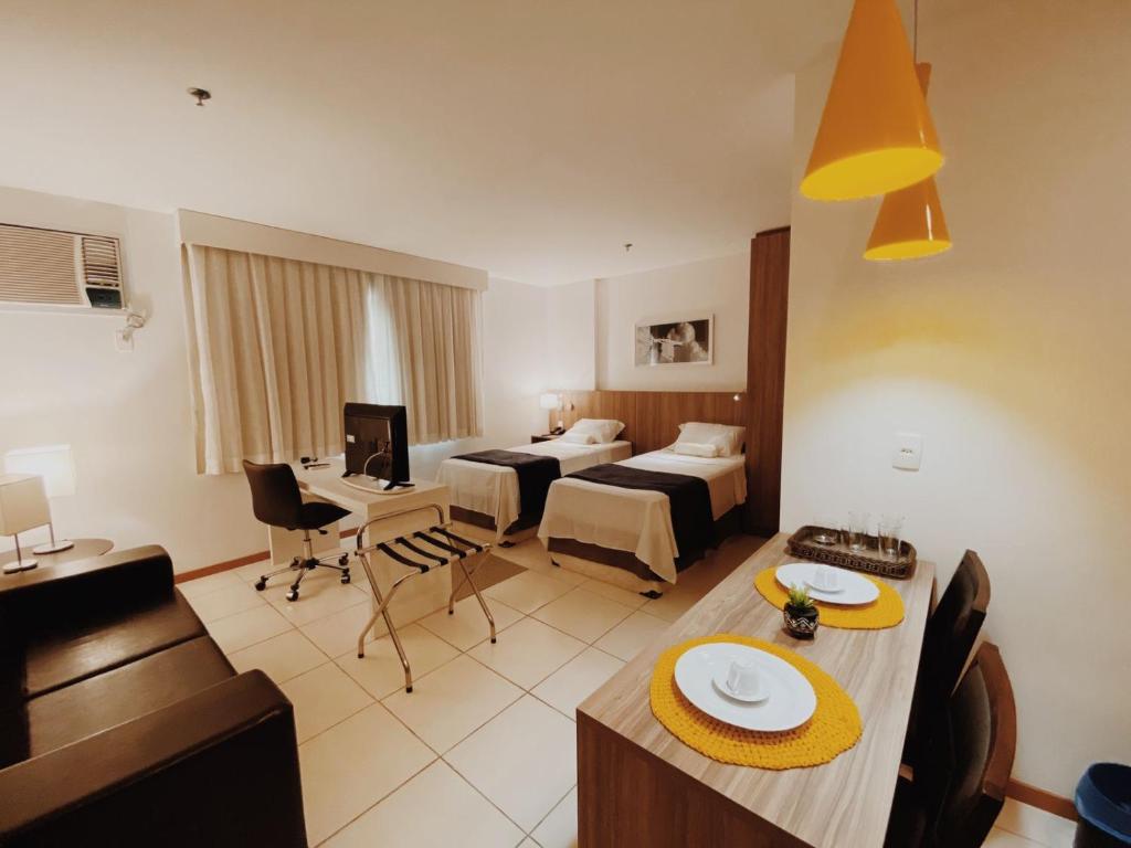 坎普斯戈伊塔卡济斯Suíte completa no centro (SOHO Campos)的一间酒店客房,配有两张床和一张餐桌