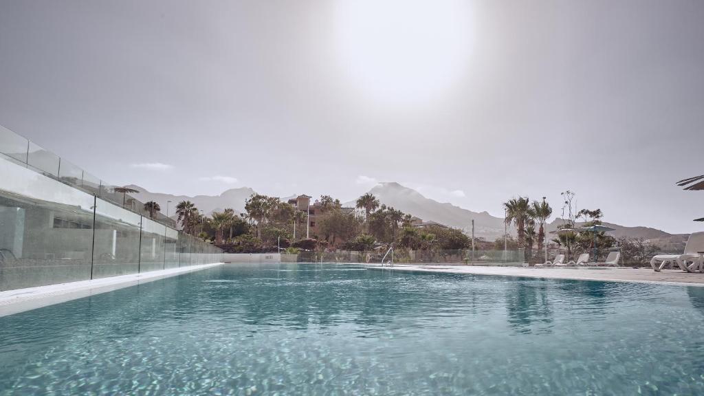 阿德耶宝吧套房酒店的蓝色的海水和山脉背景的游泳池