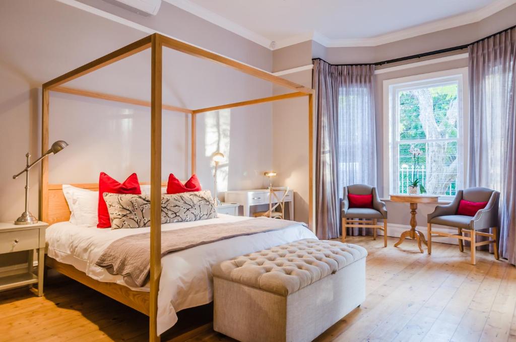 斯泰伦博斯博讷埃斯佩兰斯一室公寓的一间卧室配有一张带红色枕头的天蓬床