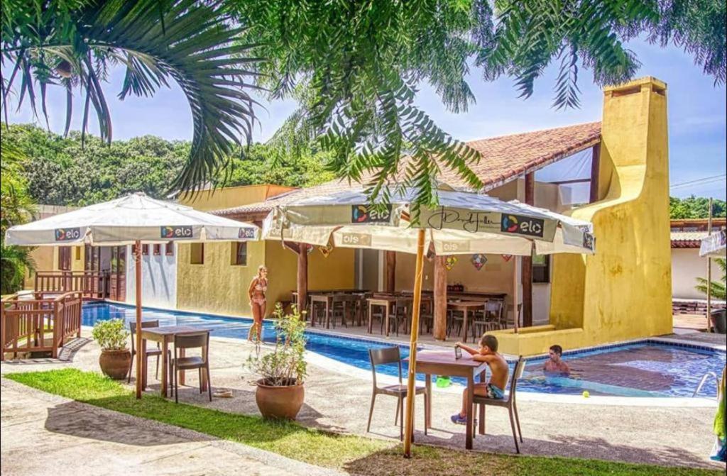 皮帕Sol da Pipa Flats Bosque da Praia的一个带桌子和遮阳伞的游泳池的度假酒店