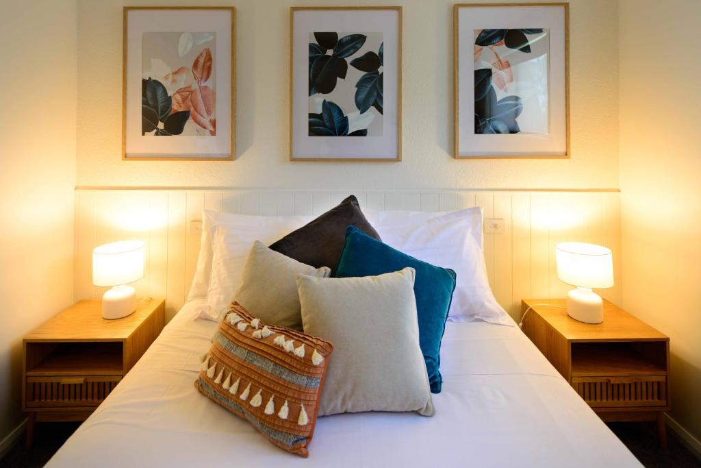圣海伦斯Georges Bay Apartments的一张带枕头的床和墙上的三张照片