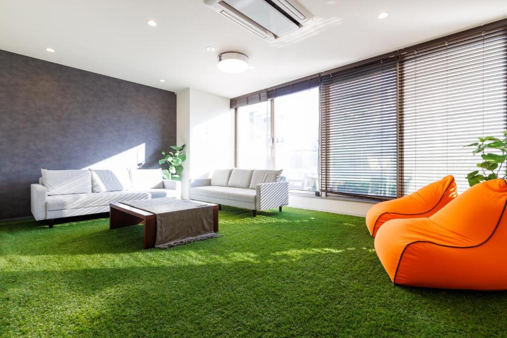 大阪STAY & GO Shinsaibashi-Kita的客厅配有橙色家具和绿色地毯