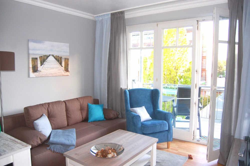 宾茨Haus Jahreszeiten Appartement Meeresrauscher by Unsere Urlaubszeit的客厅配有棕色沙发和蓝色椅子
