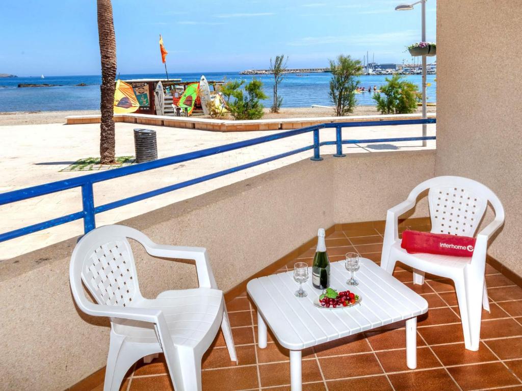 兰卡Apartment Maritim II by Interhome的两把白色椅子和一张桌子及一瓶葡萄酒