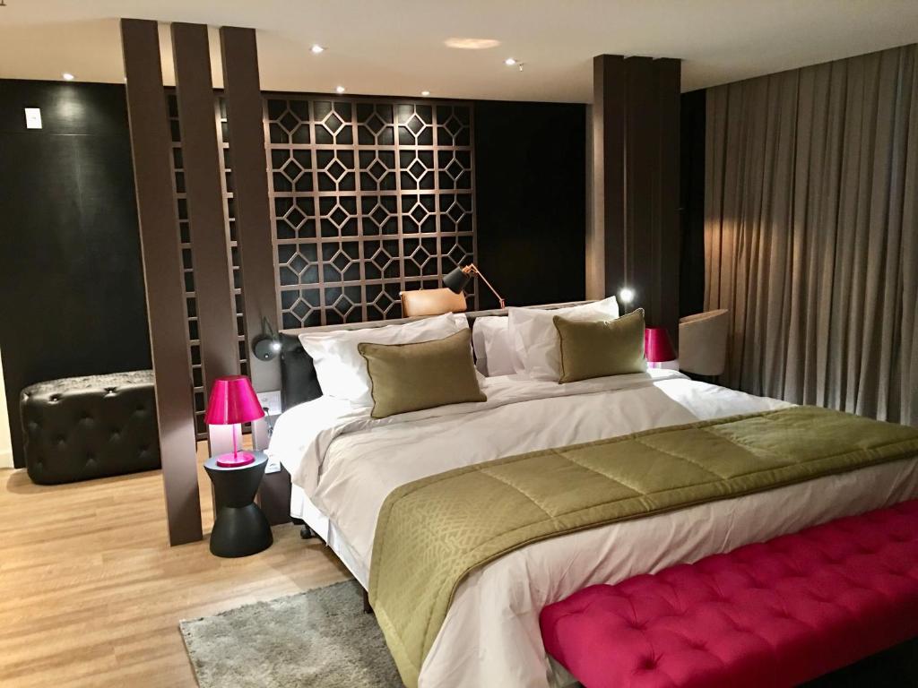 戈亚尼亚QS Marista Hotel的一间卧室配有一张大床和红色长凳