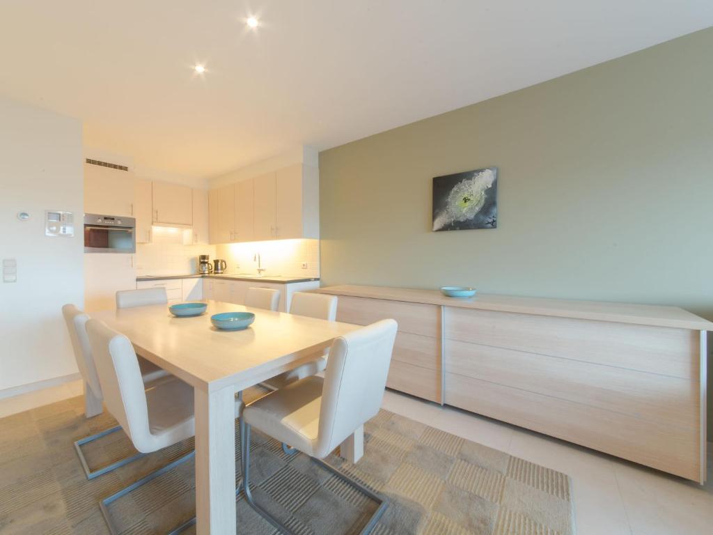 布列登Apartment Seaside 4-02 by Interhome的厨房配有木桌和白色椅子