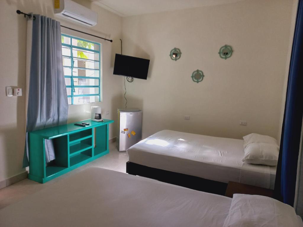 科苏梅尔Bea rooms and studios的酒店客房设有两张床和电视。