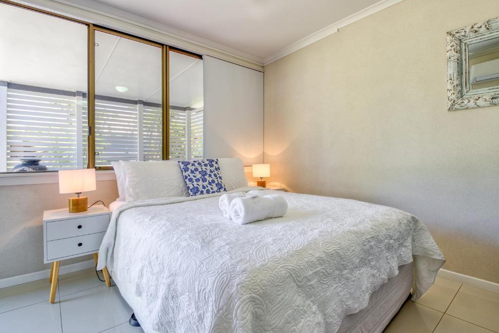 彩虹海滩Little Salty Vibes的卧室配有白色床、两盏灯和一扇窗户。