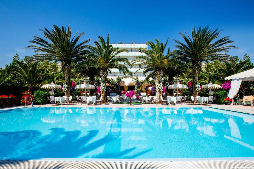 锡尔维玛丽娜Hotel Mion Charme & Relax的一座棕榈树大型游泳池和一座建筑