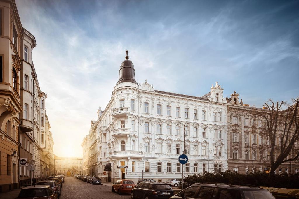 奥洛穆茨Theresian Hotel的街道上一座白色的大建筑,有汽车停放