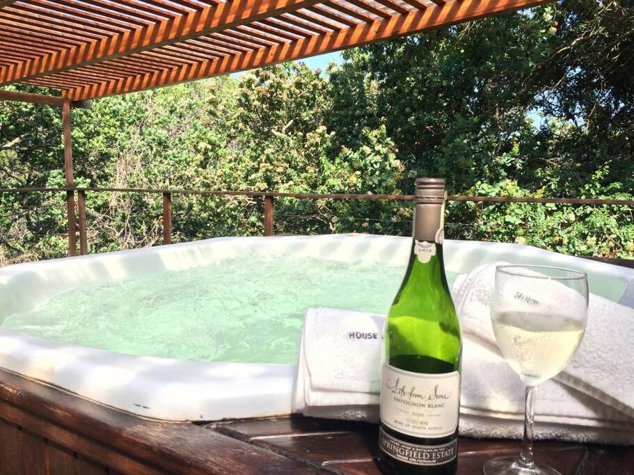 索德瓦纳湾Sodwana Bay Lodge, House 31的一瓶葡萄酒和一杯热浴盆旁的玻璃