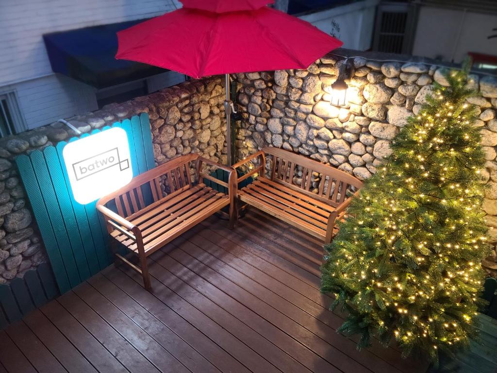 首尔Batwo Stay - For foreigners only的甲板上的圣诞树,有两把长椅和一把伞