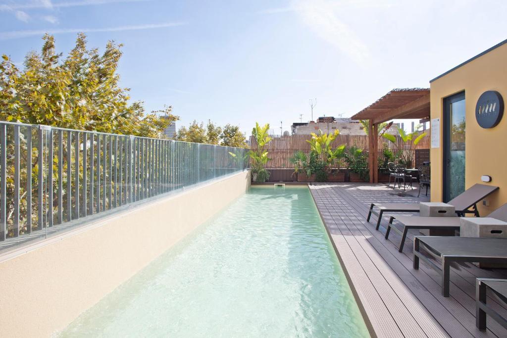 巴塞罗那纽巴塞罗那酒店的一个带桌子和长凳的阳台的游泳池