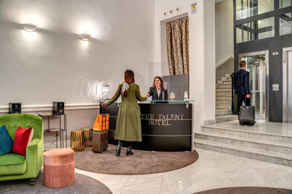罗马The Talent Hotel的站在酒店大堂柜台的女人