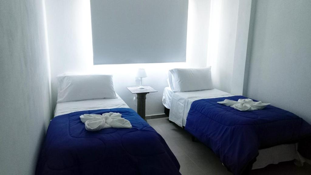 罗萨里奥Hotel Musto的配有两张床铺的客房配有蓝色床单和白色枕头
