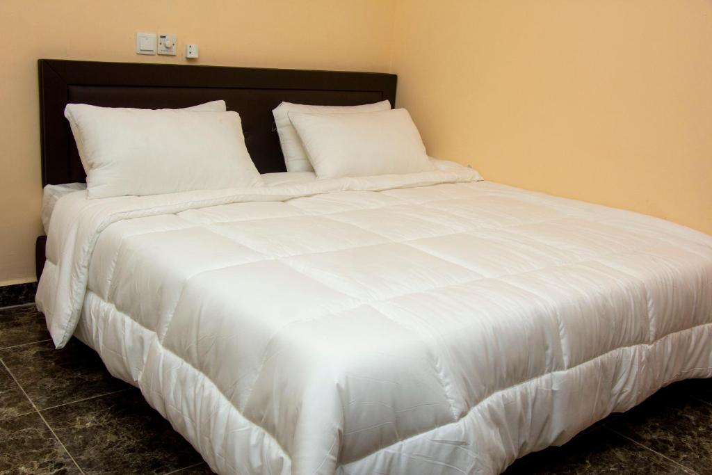 阿克拉High Level Apartment的一张白色大床,配有白色床单和枕头