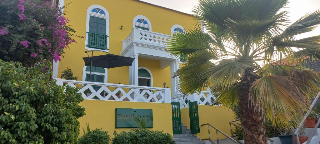 圣菲利佩Hotel Savana的一座黄色房子,前面有一棵棕榈树