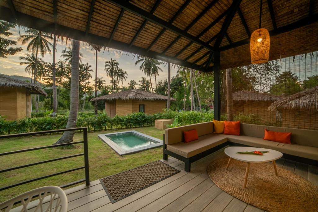 恰洛克拉姆Suan Residence - Exotic and Contemporary Bungalows with Private Pool的一个带沙发和桌子的庭院和一个游泳池