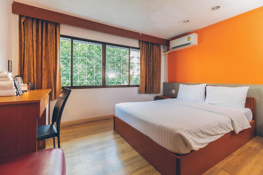 曼谷Atlas Bangkok Hotel的一间卧室配有一张床、一张书桌和窗户。