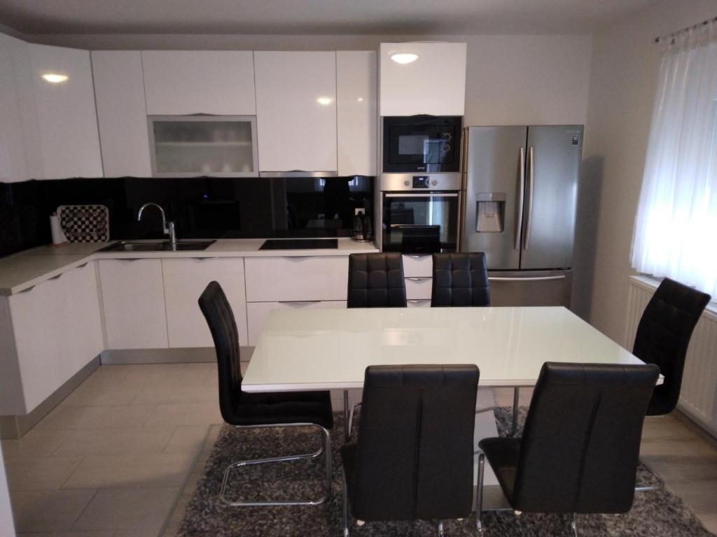 波素斯捷Apartmani Đerek的厨房配有白色的桌子和黑色的椅子