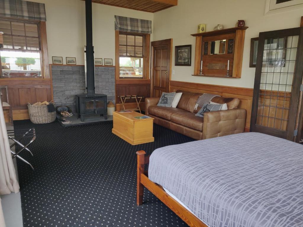 朗伊奥拉Bramley's Stables and Accommodation的一间卧室配有一张床、一张沙发和一个壁炉