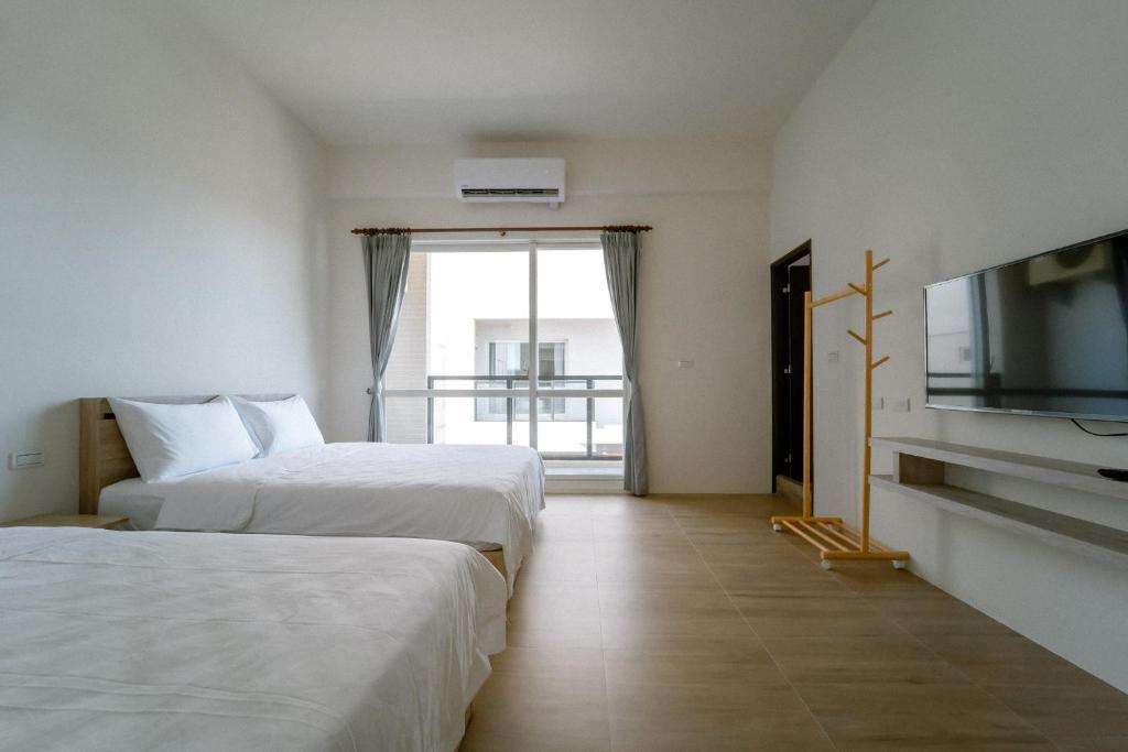 Huxi澎湖逸軒居民宿的酒店客房设有两张床和一台平面电视。