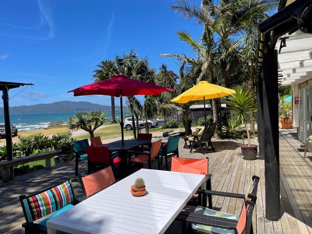 库珀海滩Driftwood Lodge Beachfront, Cable Bay, Coopers Beach, Northland的一张桌子和椅子,配有遮阳伞和海滩