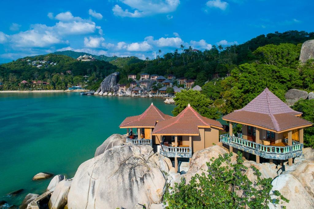 涛岛Koh Tao Relax Freedom Beach Resort的水中岩石顶上的一群房子