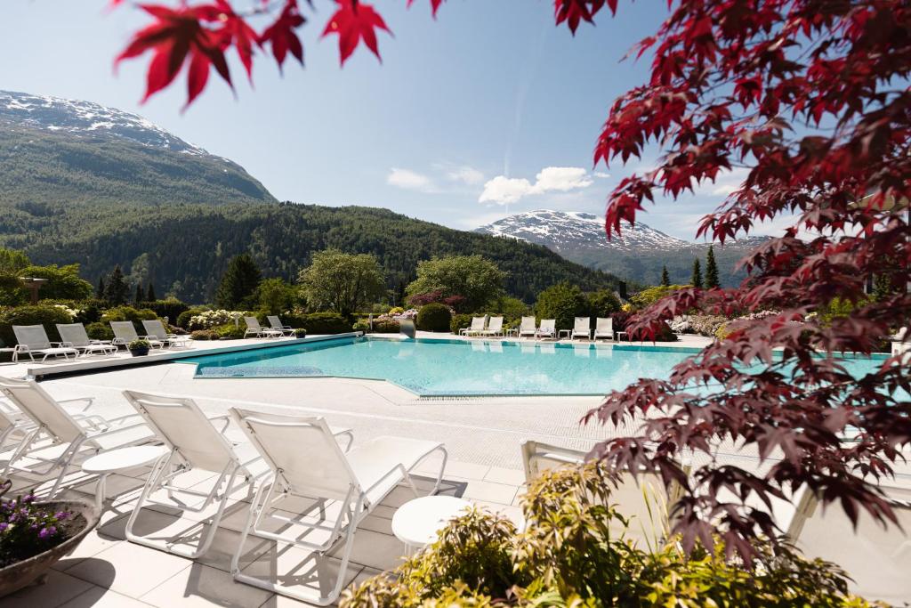 卢恩Hotel Alexandra Loen的一个带椅子的游泳池,背景是群山