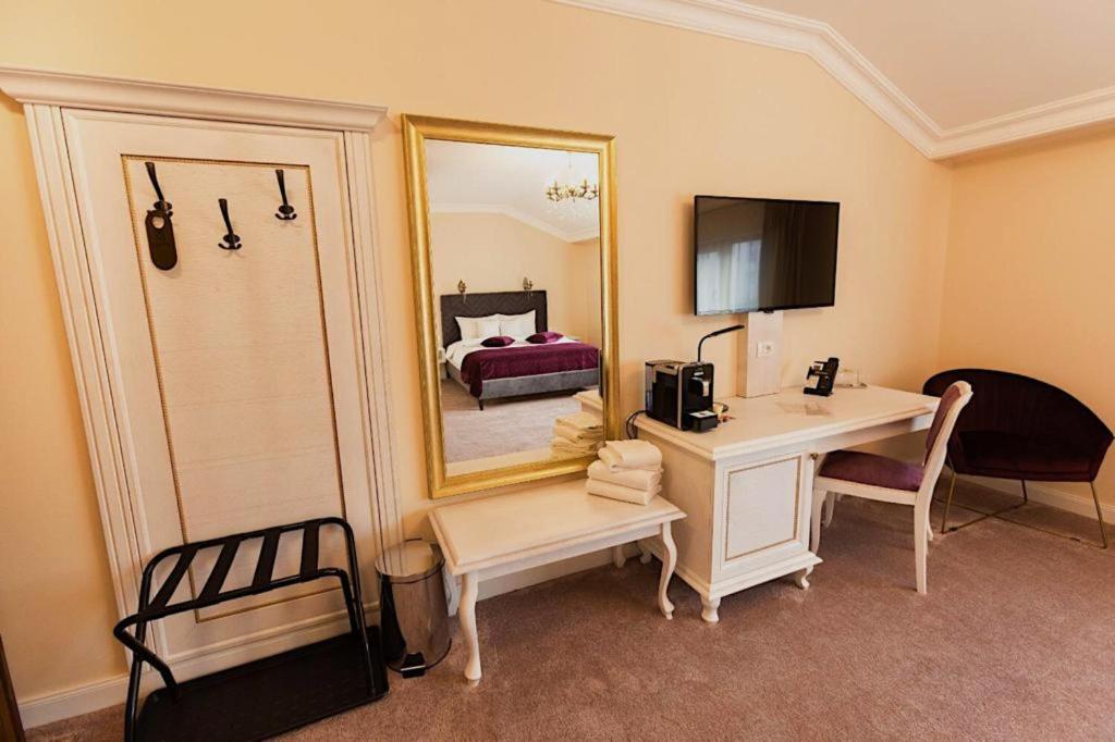 布拉索夫4Cardinal's Hotel Boutique的客房设有书桌和带镜子的床。