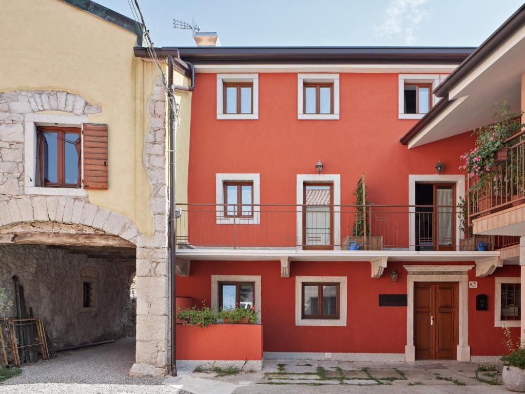 的里雅斯特Crocevia - Locanda carsica contemporanea的红色的房子,在庭院里设有阳台