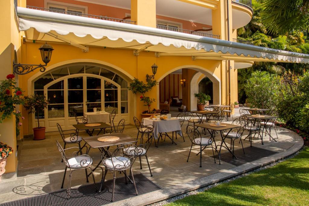 坎诺比奥Villa Palmira Kinderfreies Hotel的建筑前设有带桌椅的户外庭院。