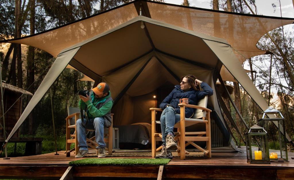 乌鲁班巴Glamping Chaska Ocupi的坐在帐篷里的男人和女人