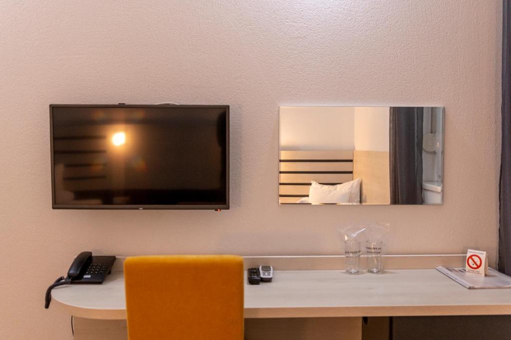 诺维萨德Garni Hotel 11tica DM的客房设有一张桌子、一台电视和一张黄色的椅子