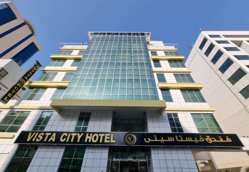 迪拜Vista City Hotel的两个高楼前的美国城市酒店标志