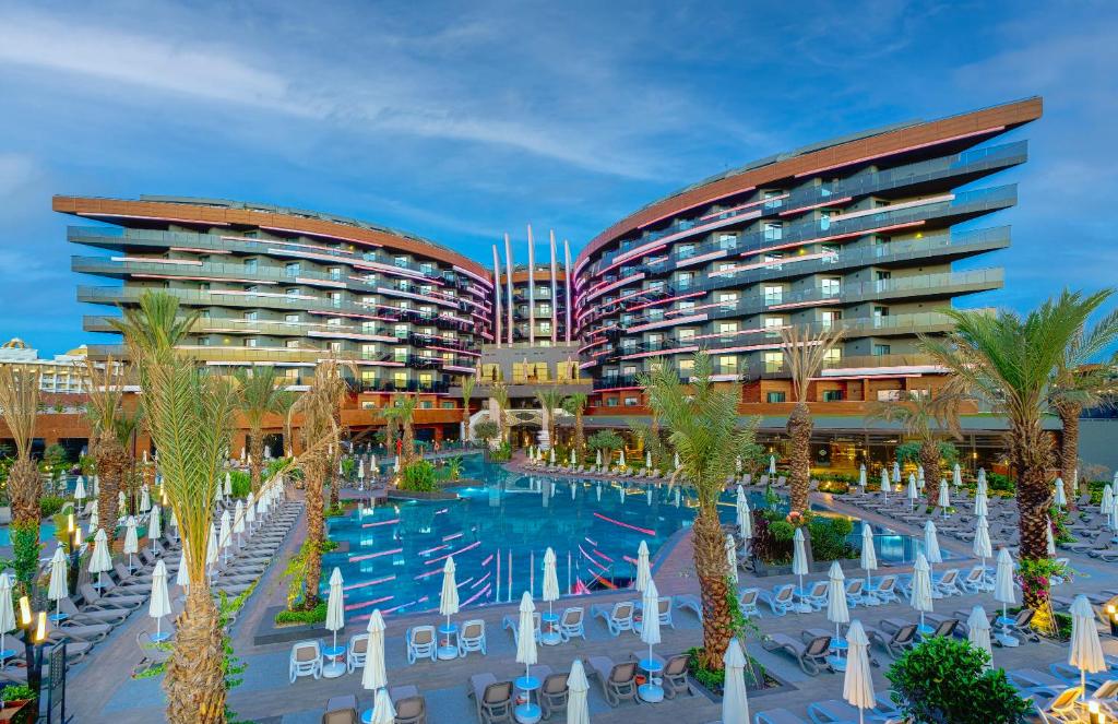 锡德Kirman Calyptus Resort & SPA的一座拥有游泳池和棕榈树的酒店