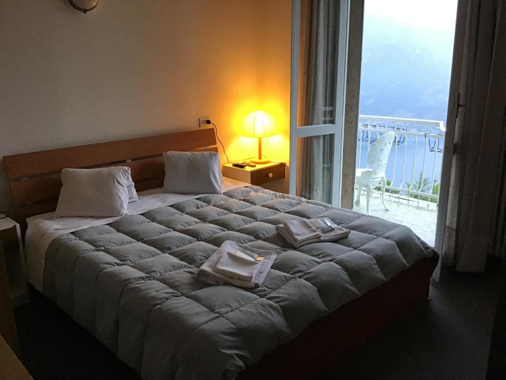贝拉吉奥LOCANDA MIRABEAU的一间卧室设有一张大床和大窗户