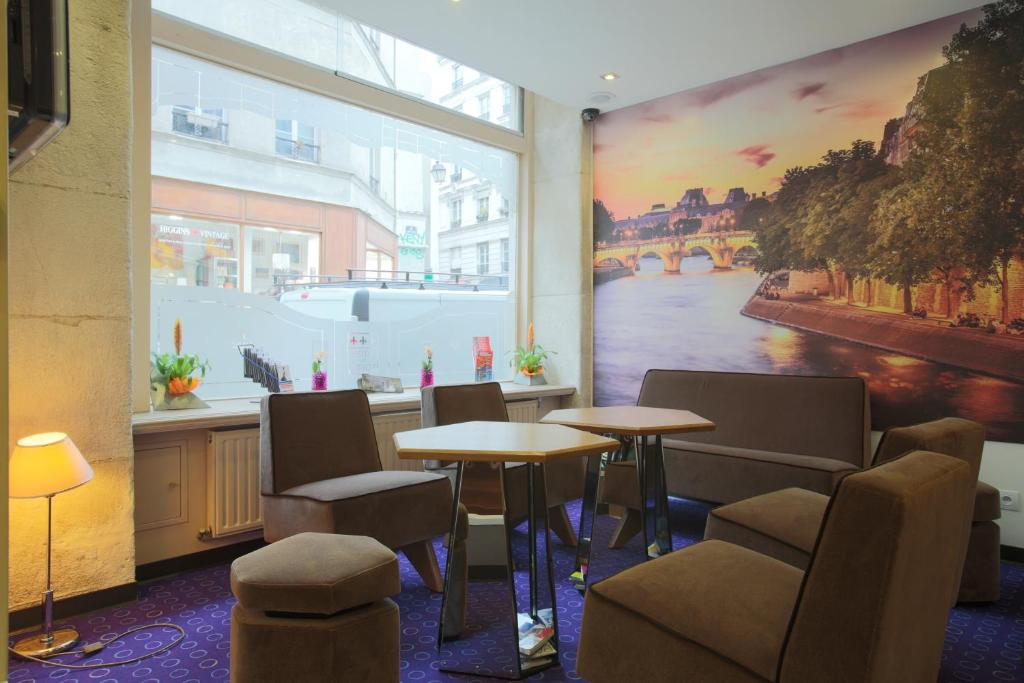 巴黎杜卢瓦雷大酒店的一间设有桌椅的房间和墙上的绘画