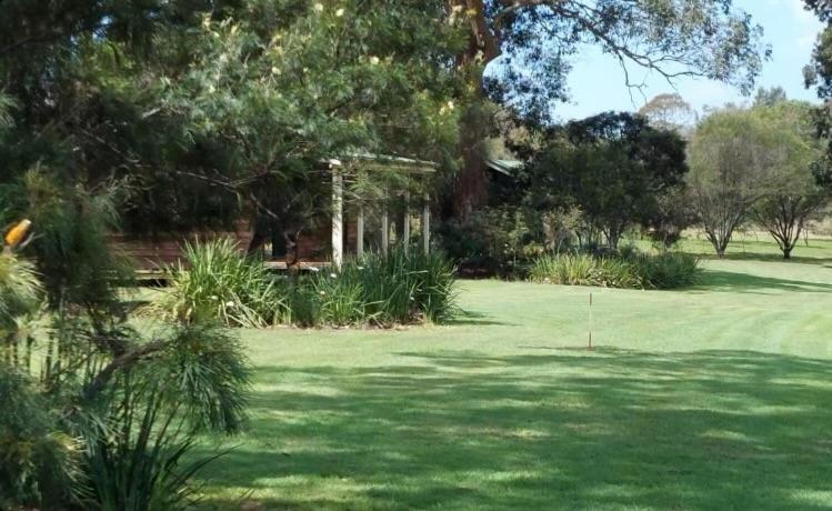 勒弗戴尔Cabins at Lovedale Wedding Chapel的郁郁葱葱的绿色庭院,种植了树木,设有高尔夫球场