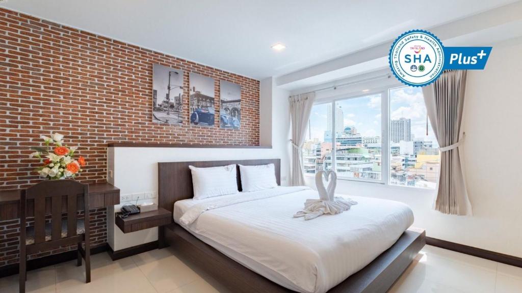 合艾合艾友酒店的一间卧室设有一张床和砖墙