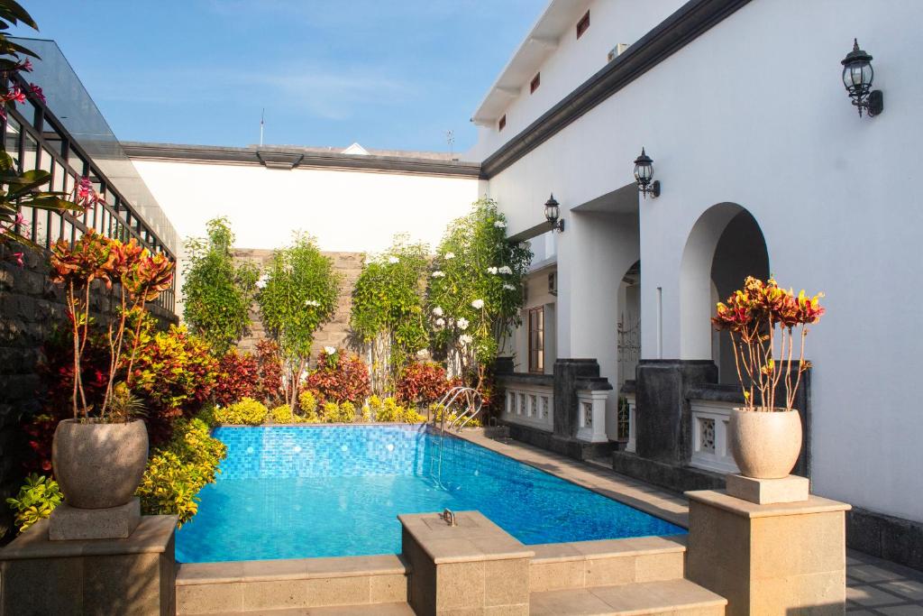 岩望Daroessalam Syariah Heritage Hotel的植物繁茂的建筑中间的游泳池