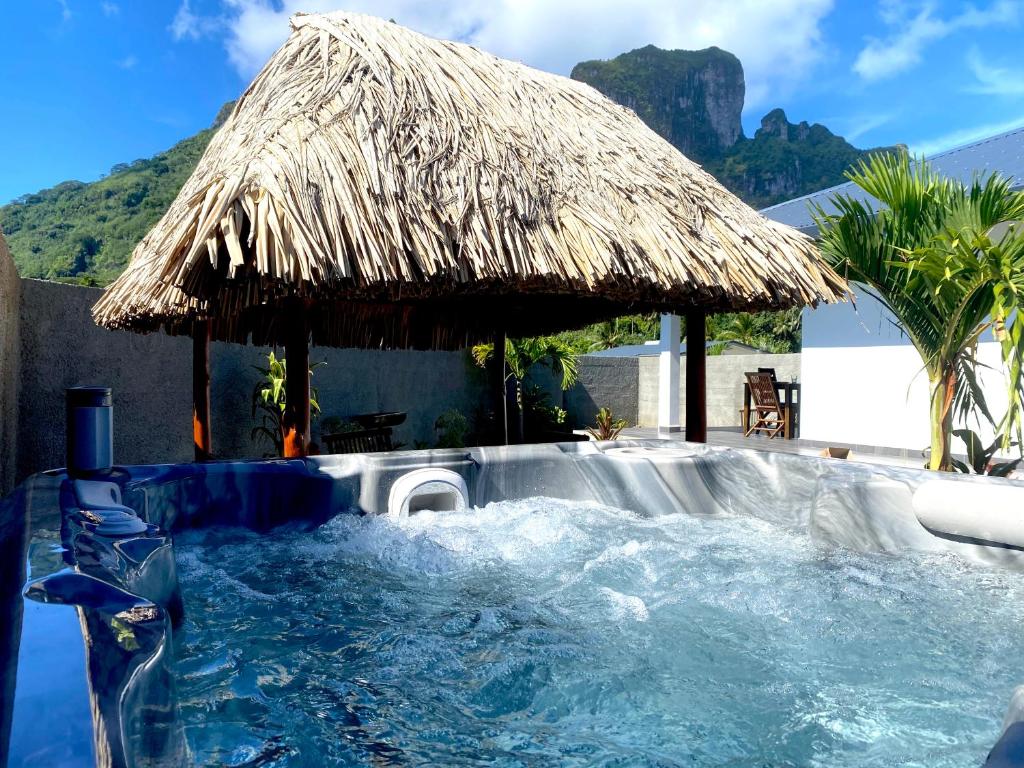 波拉波拉Anaiva Lodge Bora的一个带茅草伞的游泳池和一个游泳池