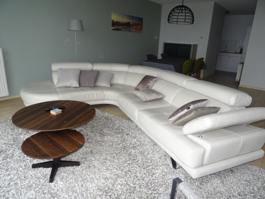 布雷斯肯斯Kustverhuur, Appartement aan Zee, Prachtig appartement op de begane grond PS 13-001的客厅配有一张白色沙发,配有一张桌子
