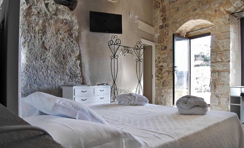 希克利Borgo Hedone的卧室配有白色的床和墙上的电视。