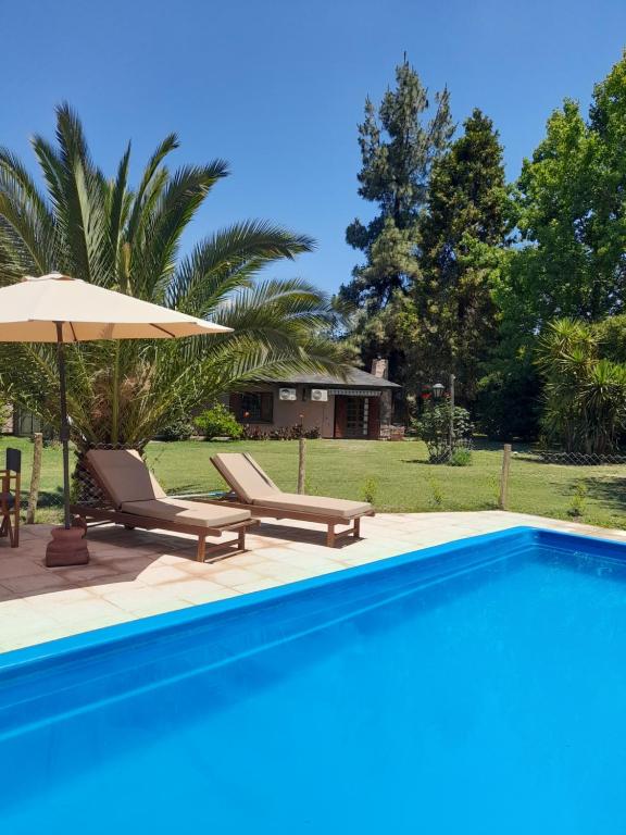 查克拉斯德科里亚Alto Chacras Cottage的一个带2把躺椅和遮阳伞的游泳池