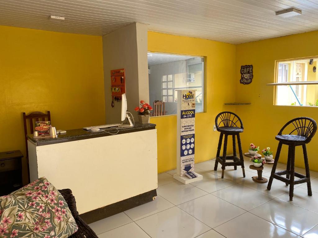 巴纳伊巴Pousada Do Sol的一间厨房,里面设有黄色的墙壁和两张凳子