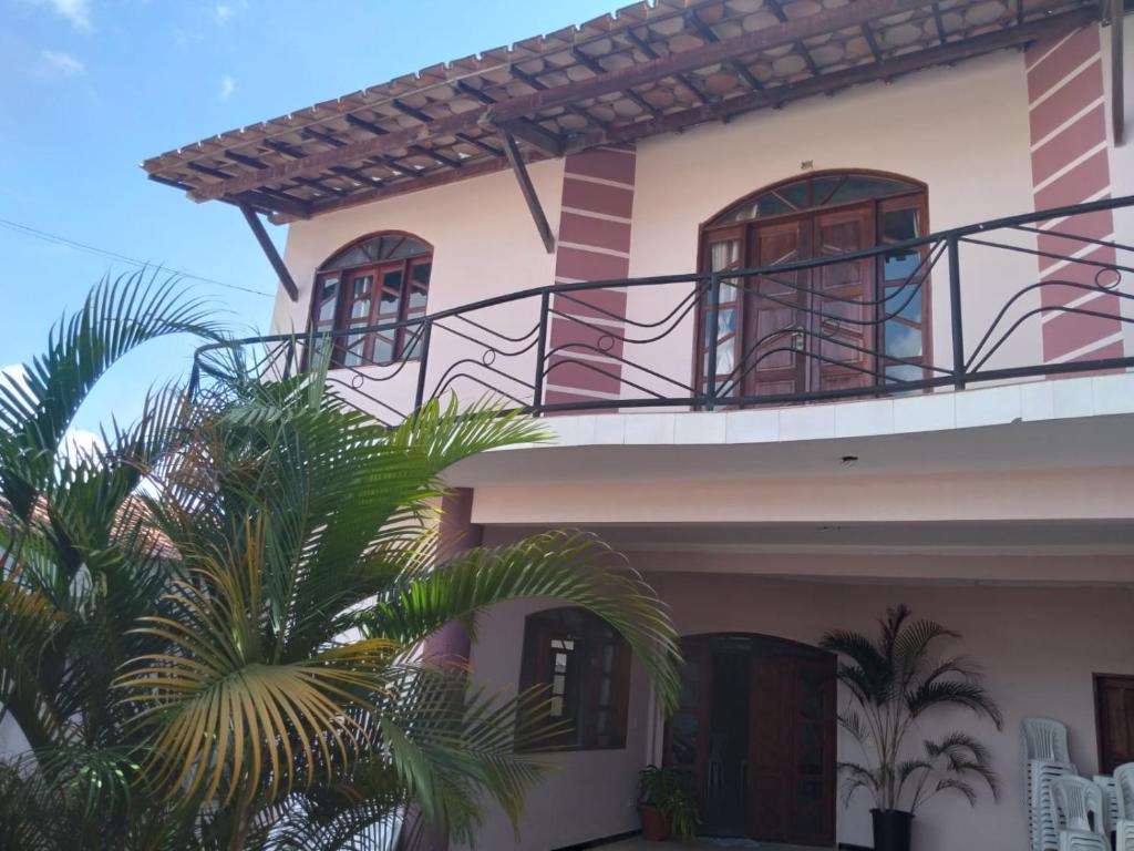 伊比科阿拉Pousada Emanuell的带阳台的房屋,前面有棕榈树